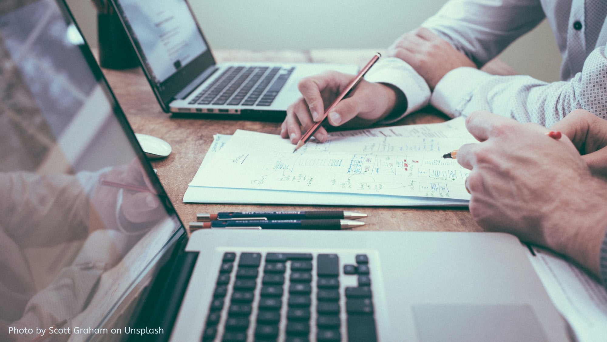 workers looking at paper beside laptop